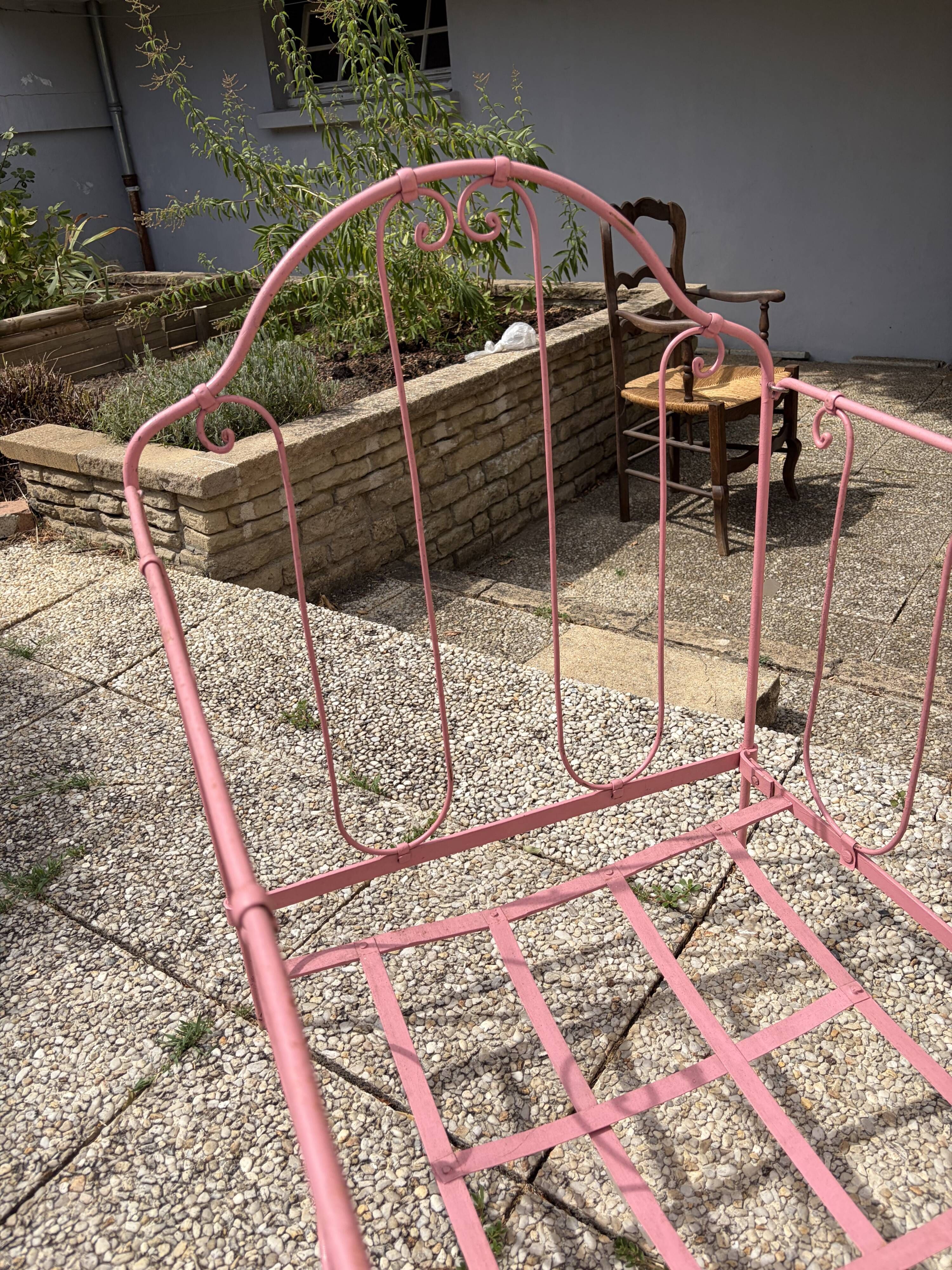 Old iron bed for children, painted pink with scrolls, romantic style.