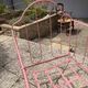 Old iron bed for children, painted pink with scrolls, romantic style.
