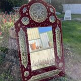 Large oriental mirror with embossed brass decoration on a red velvet background