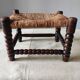 Antique wooden turned spool footrest with straw.