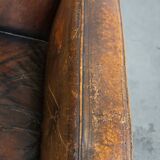 Fauteuil ancien en cuir de mouton sur roulettes et patiné