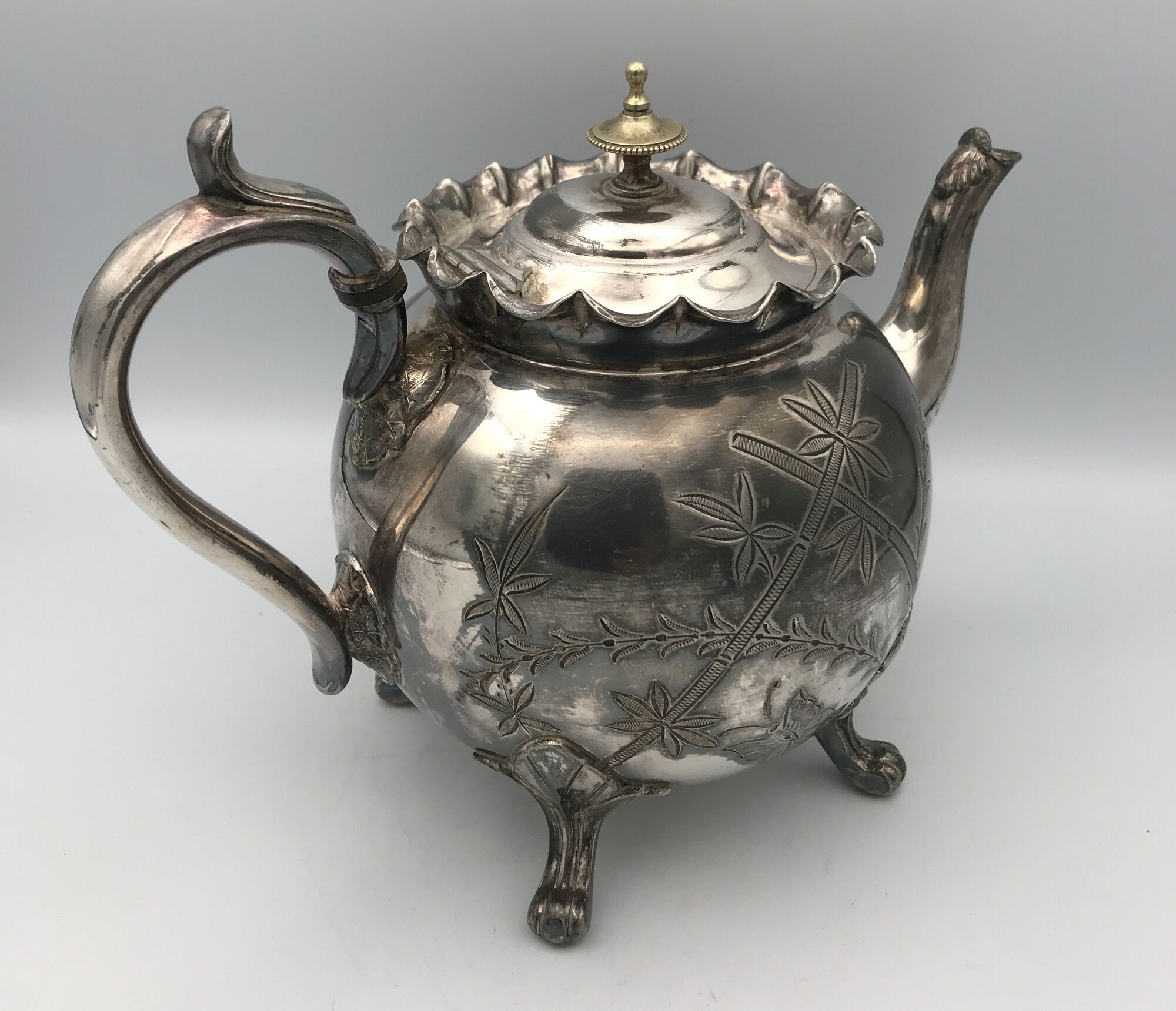 Old teapot pourer in silver metal decorated with foliage and butterflies