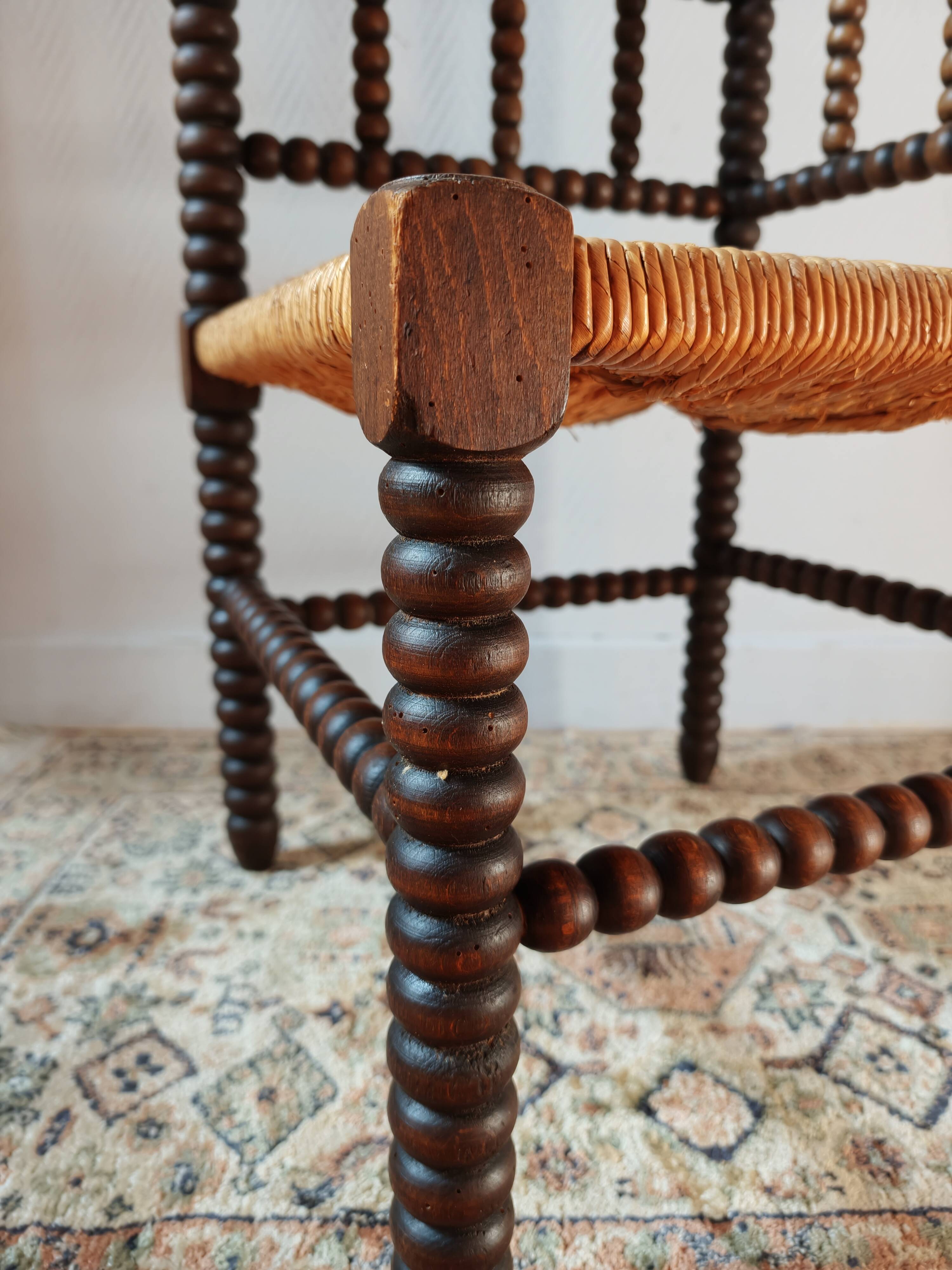 Old wooden turned spindle fireside chair with a straw seat.