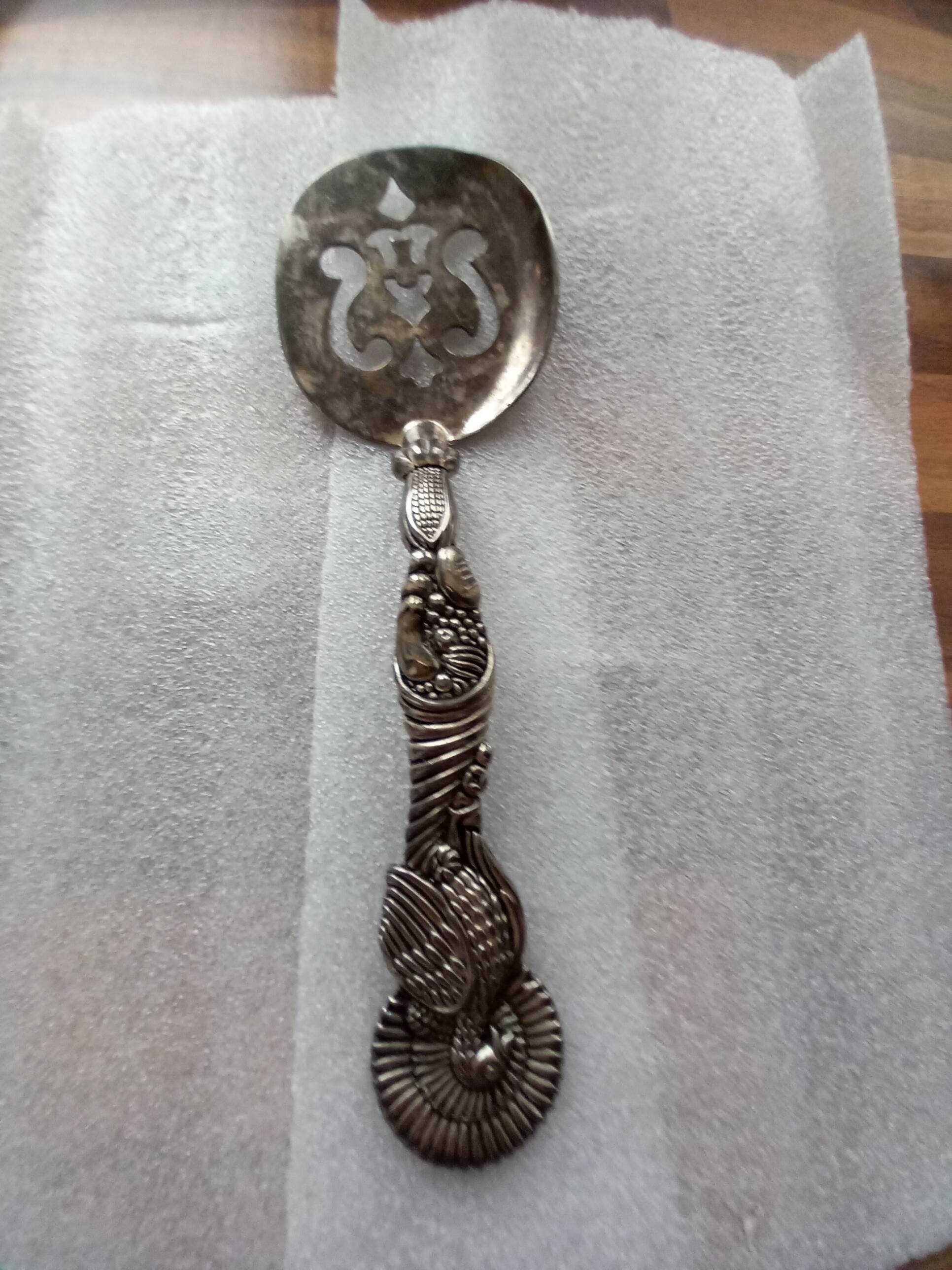 Vintage serving spoon with a carved relief handle.