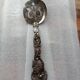 Vintage serving spoon with a carved relief handle.