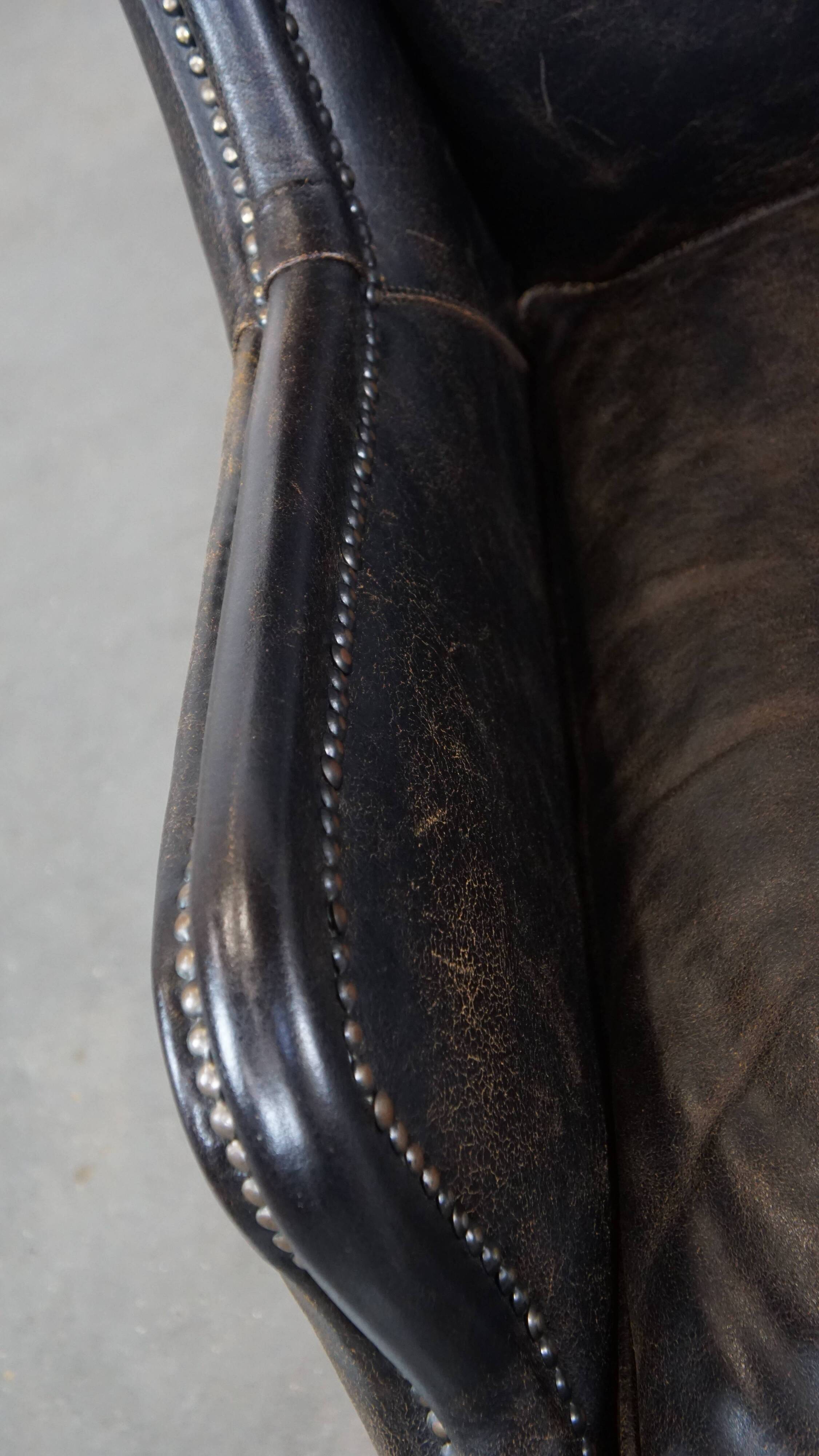 Black cow leather armchair in industrial style finished with decorative nails