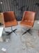 Pair of swivel chairs in cognac brown faux leather.
