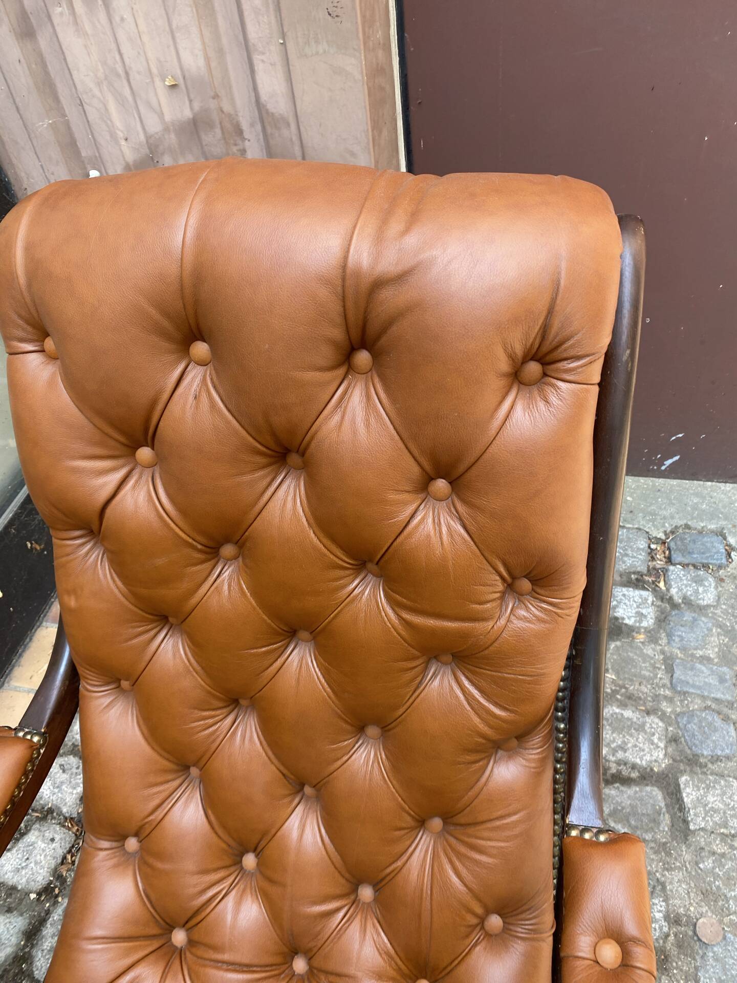 Chesterfield armchair in leather and carved solid wood