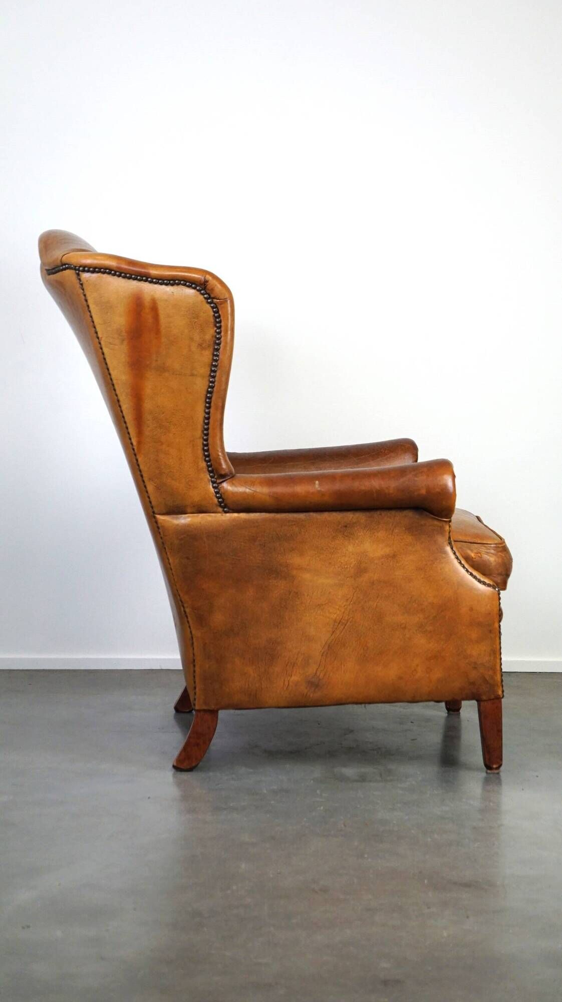 Positively lived-in sheepskin leather wing chair with pleasant seating comfort