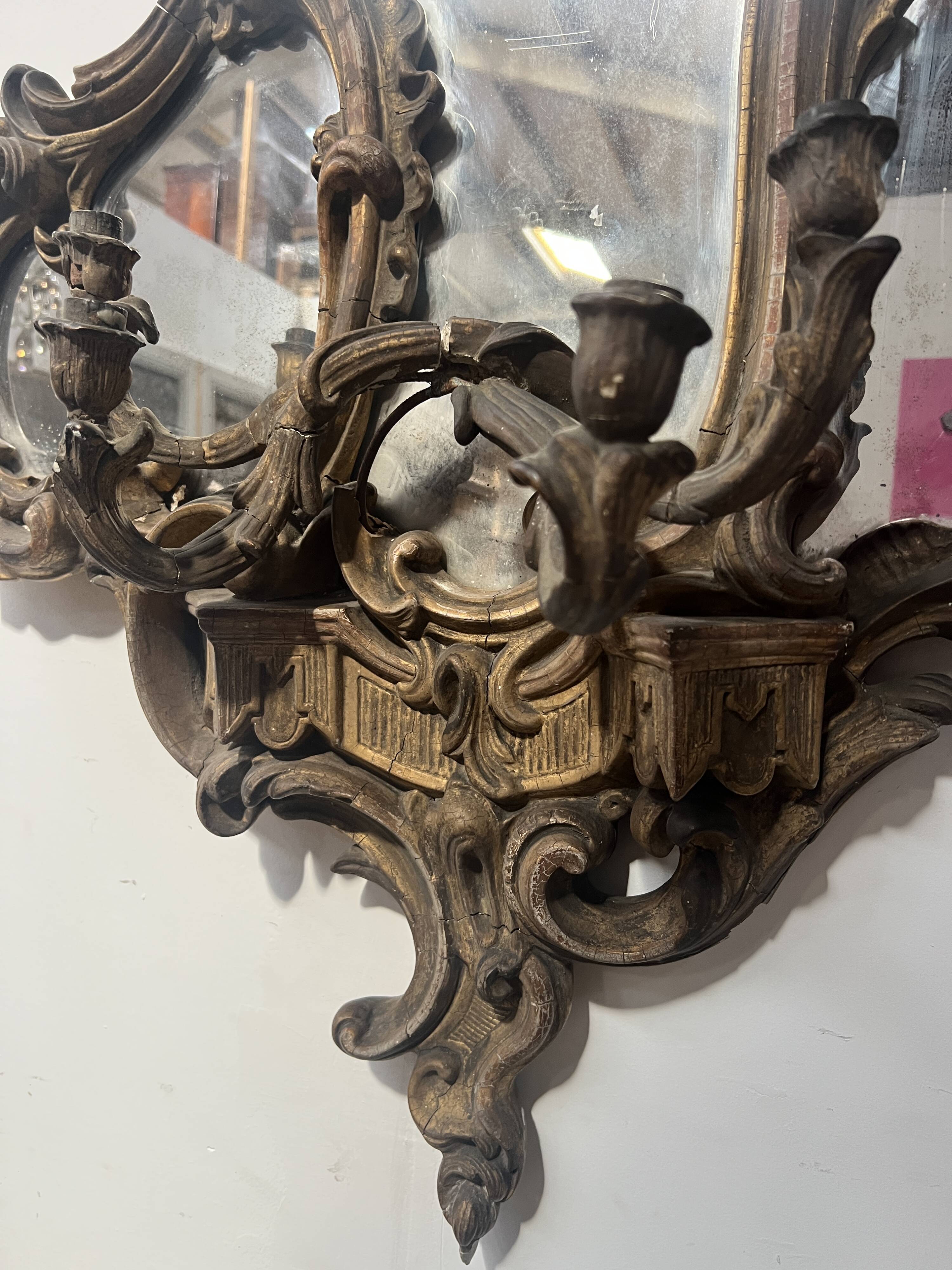 Mirror with a decorative frame featuring a four-light wall sconce, 19th century.