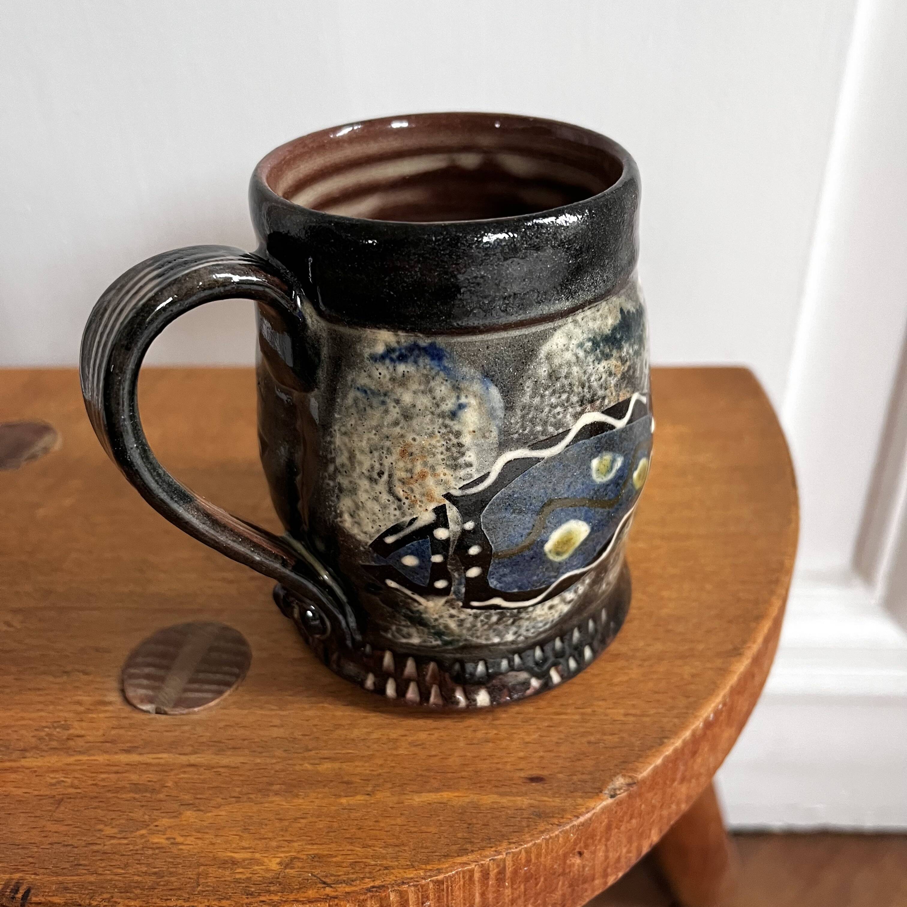 Vintage terracotta mugs with glazed designs and flower/fish motifs