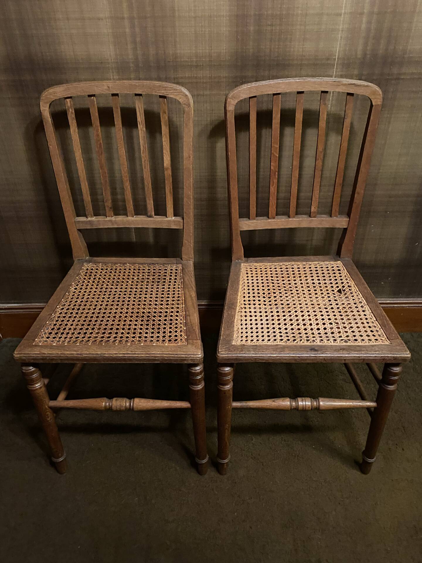 Set of 2 antique wooden chairs with caned seats.