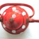 Old vintage kettle in red enamelled sheet metal, with white polka dots