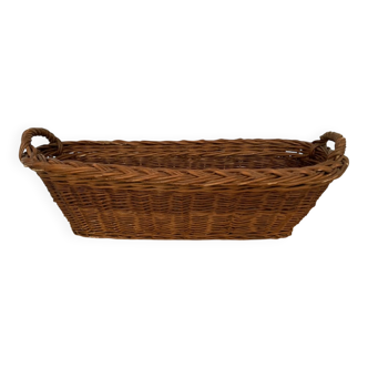 Vintage brown wicker baguette basket, elongated shape, with integrated handles.