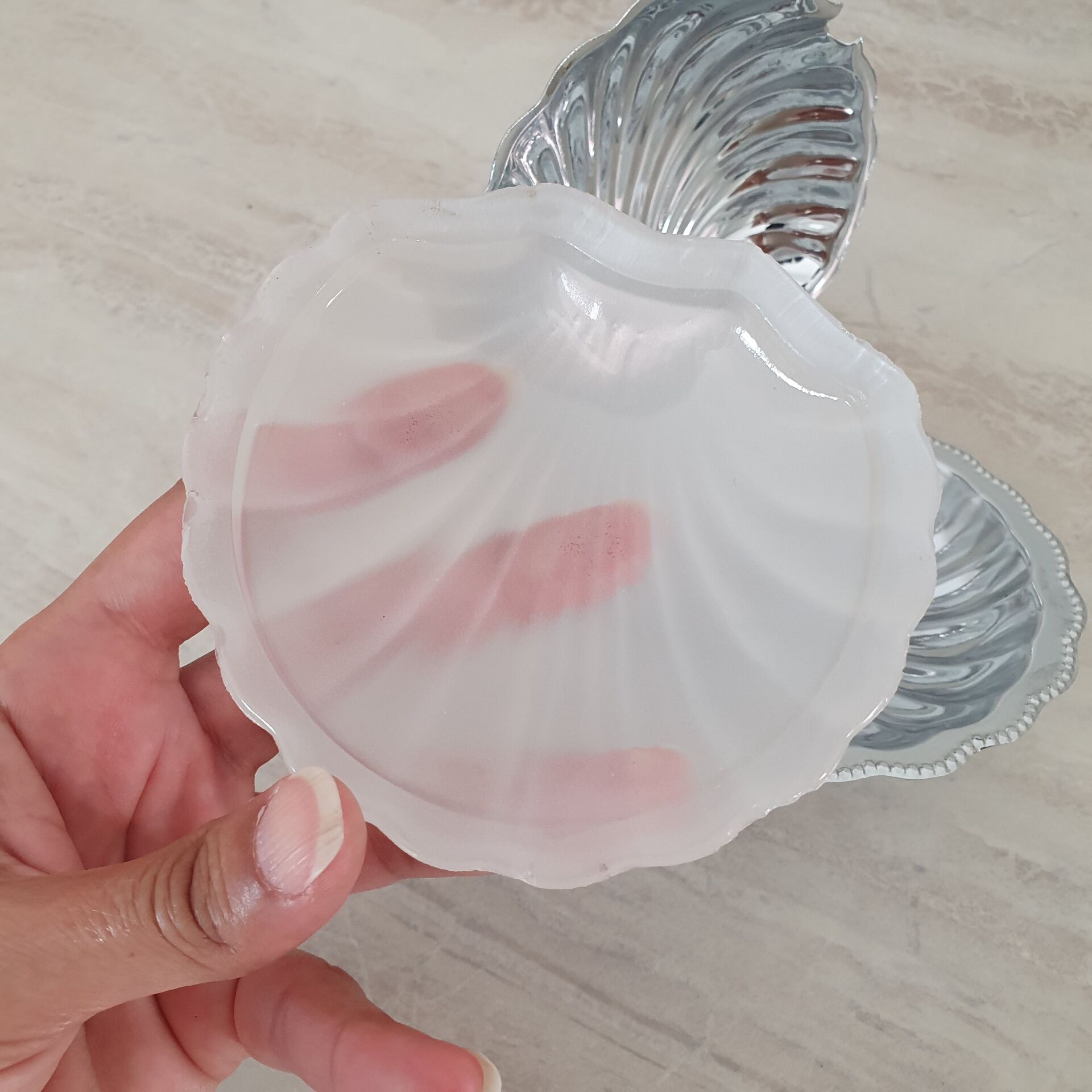 Shell-shaped butter dish in stainless steel and white glass bowl.