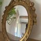 Oval convex witch mirror with golden ribbon mouldings.