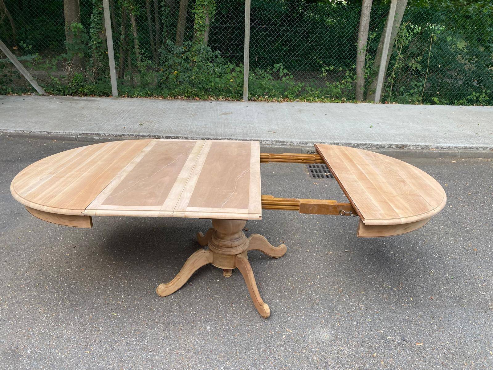 Round dining table with a central pedestal, extendable, stripped in solid walnut with 2 extensions.