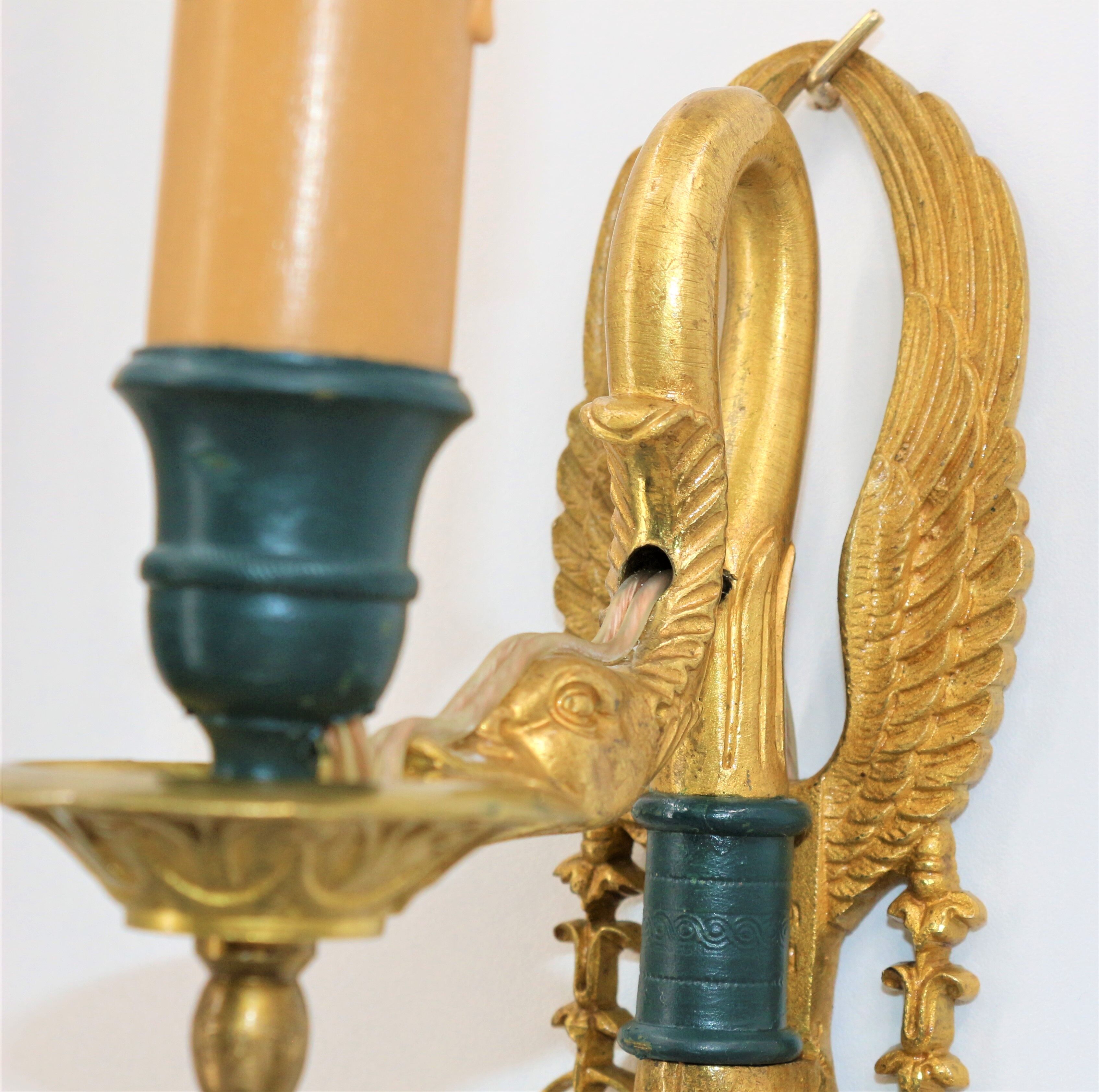 Pair of golden bronze wall lamps in triumphant empire swan style