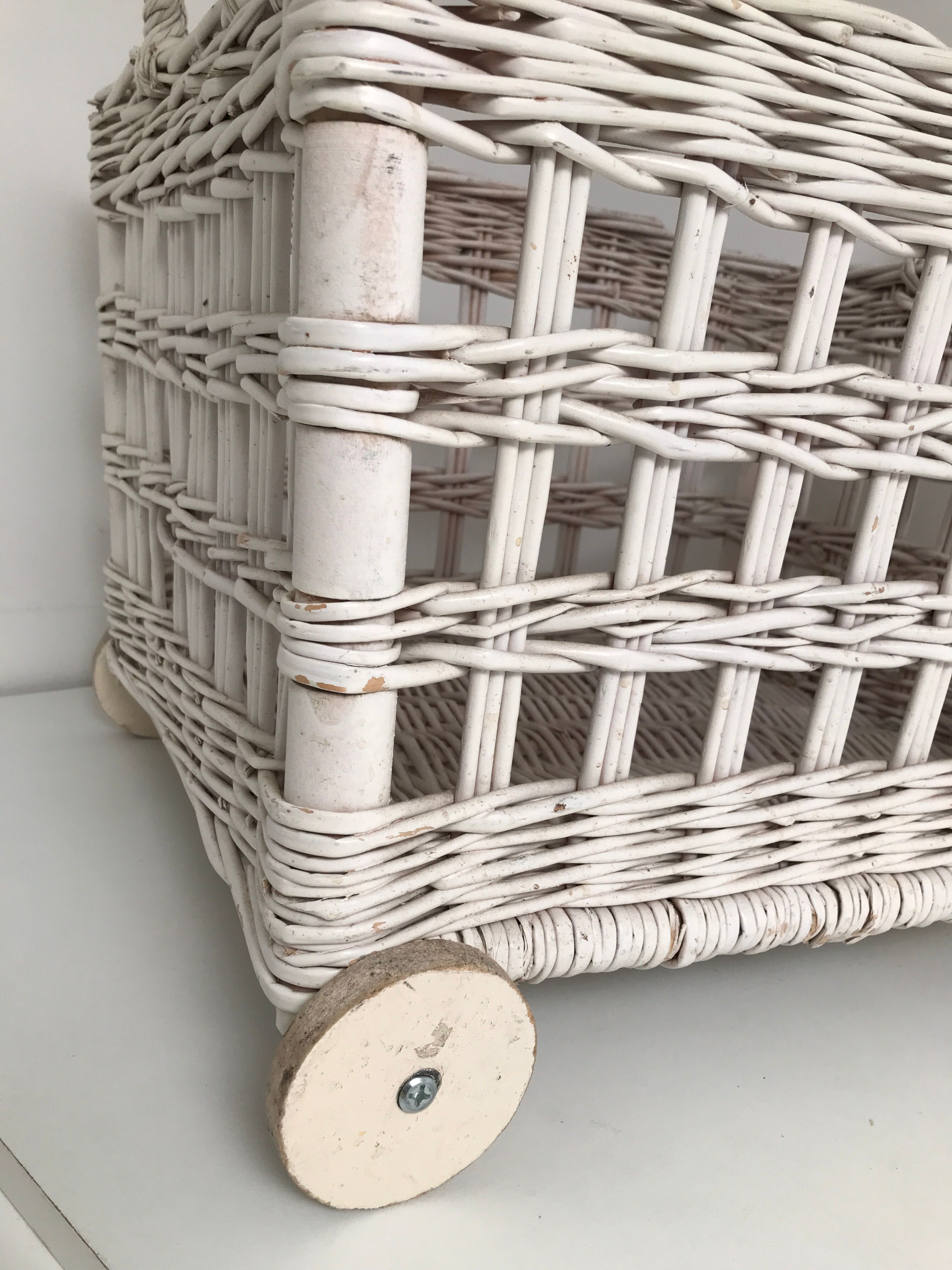 Wicker laundry basket on vintage wooden wheels