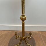 A round, neoclassical-style brass side table with a base decorated with dolphins and a red celluloid top encircled by an openwork gallery, attributed to the House of Jansen.