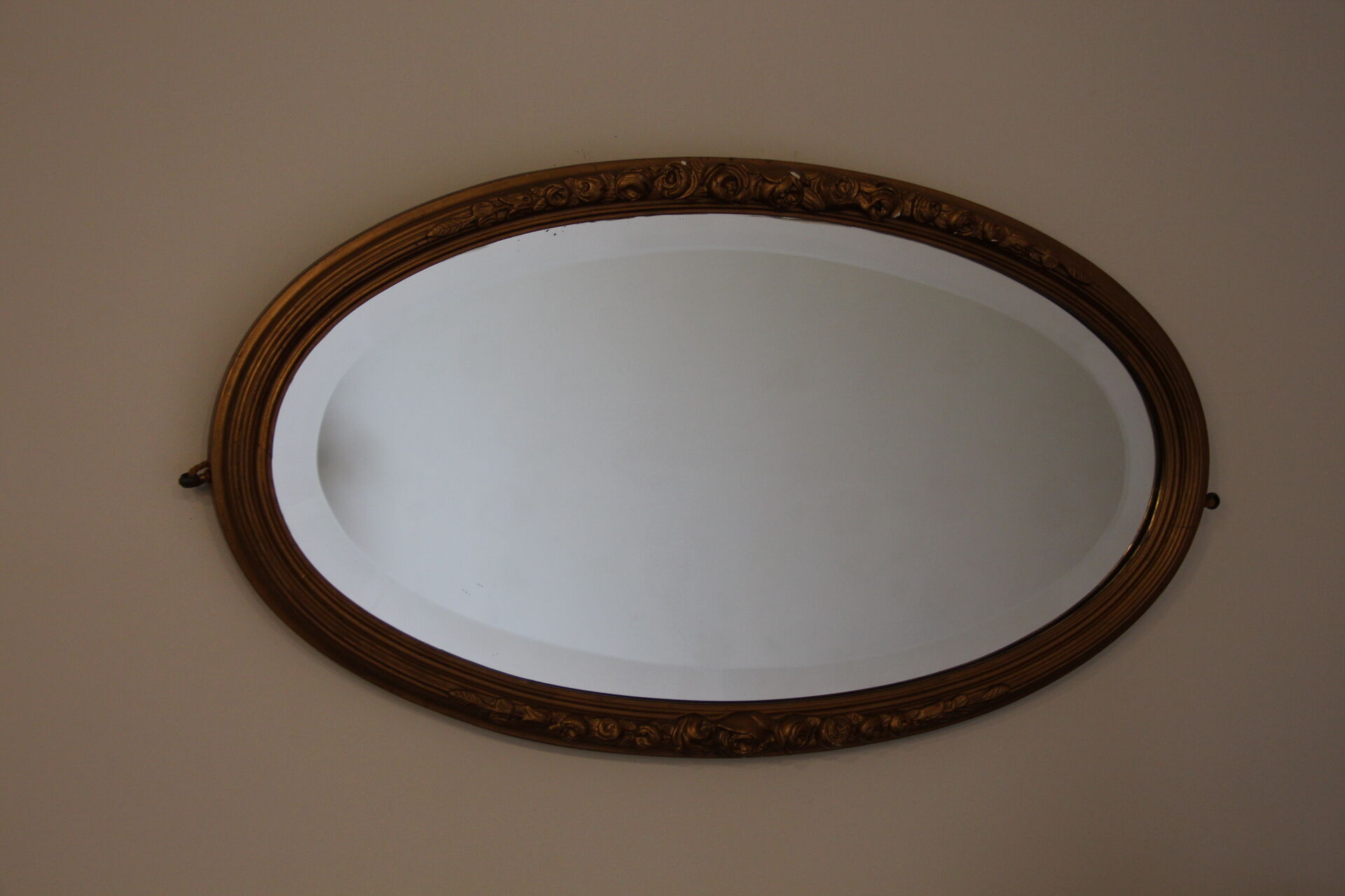 Beveled oval mirror in gilded wood