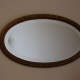 Beveled oval mirror in gilded wood