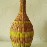 Vintage glass bottle covered with hand-woven wicker and scoubidou, with a handle
