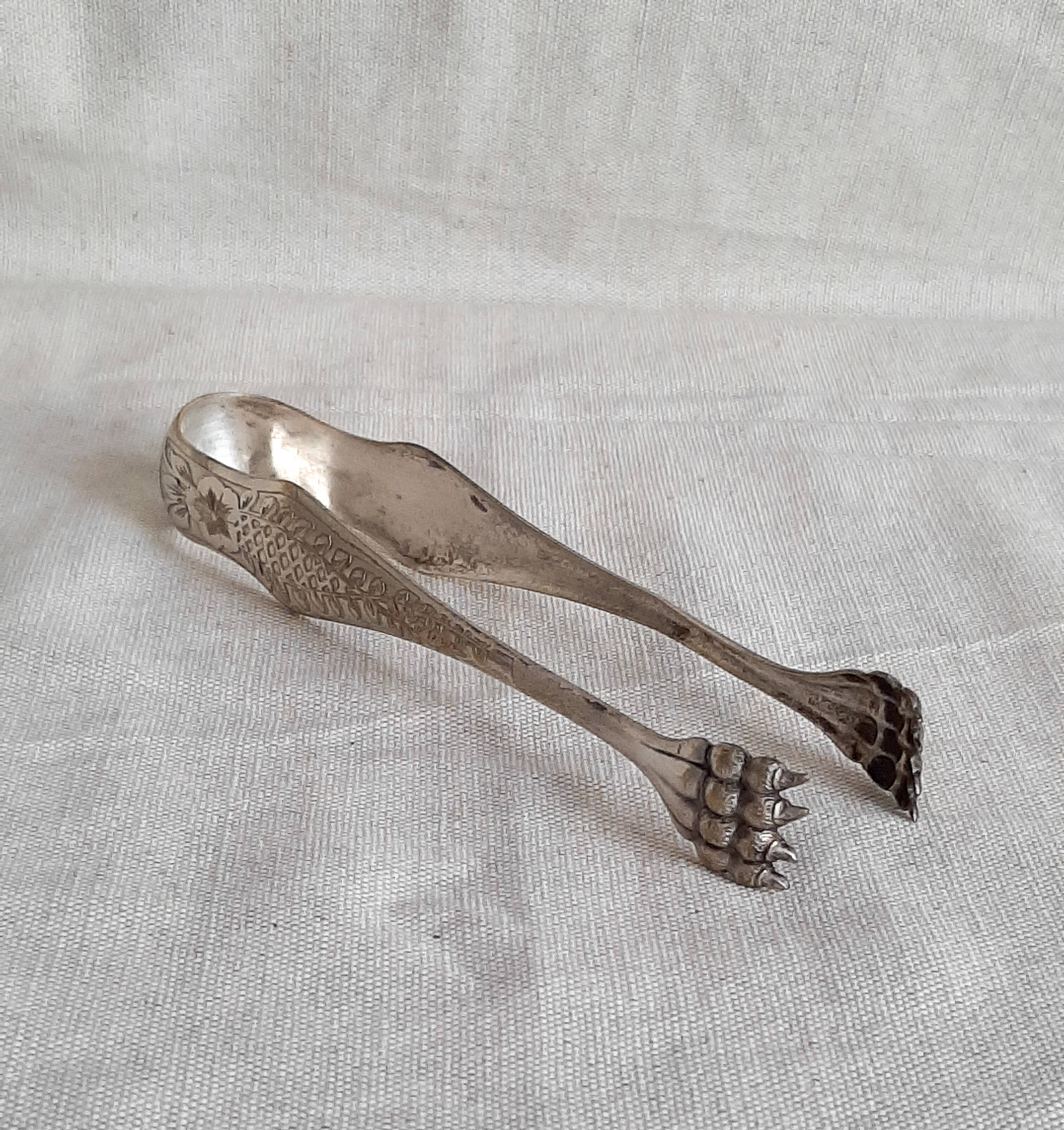 Antique silver-plated sugar tongs with lion's paws.