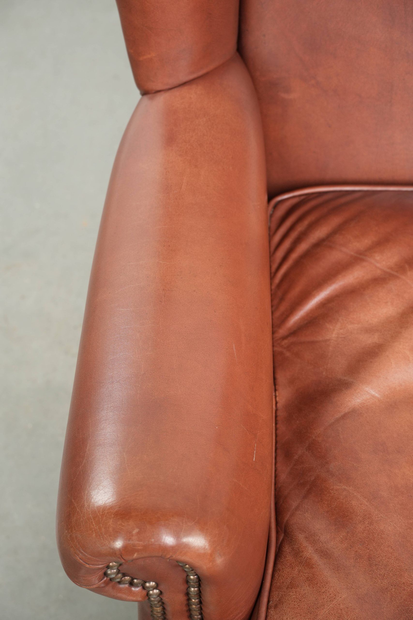 Cognac-coloured cow leather wingback armchair in English style