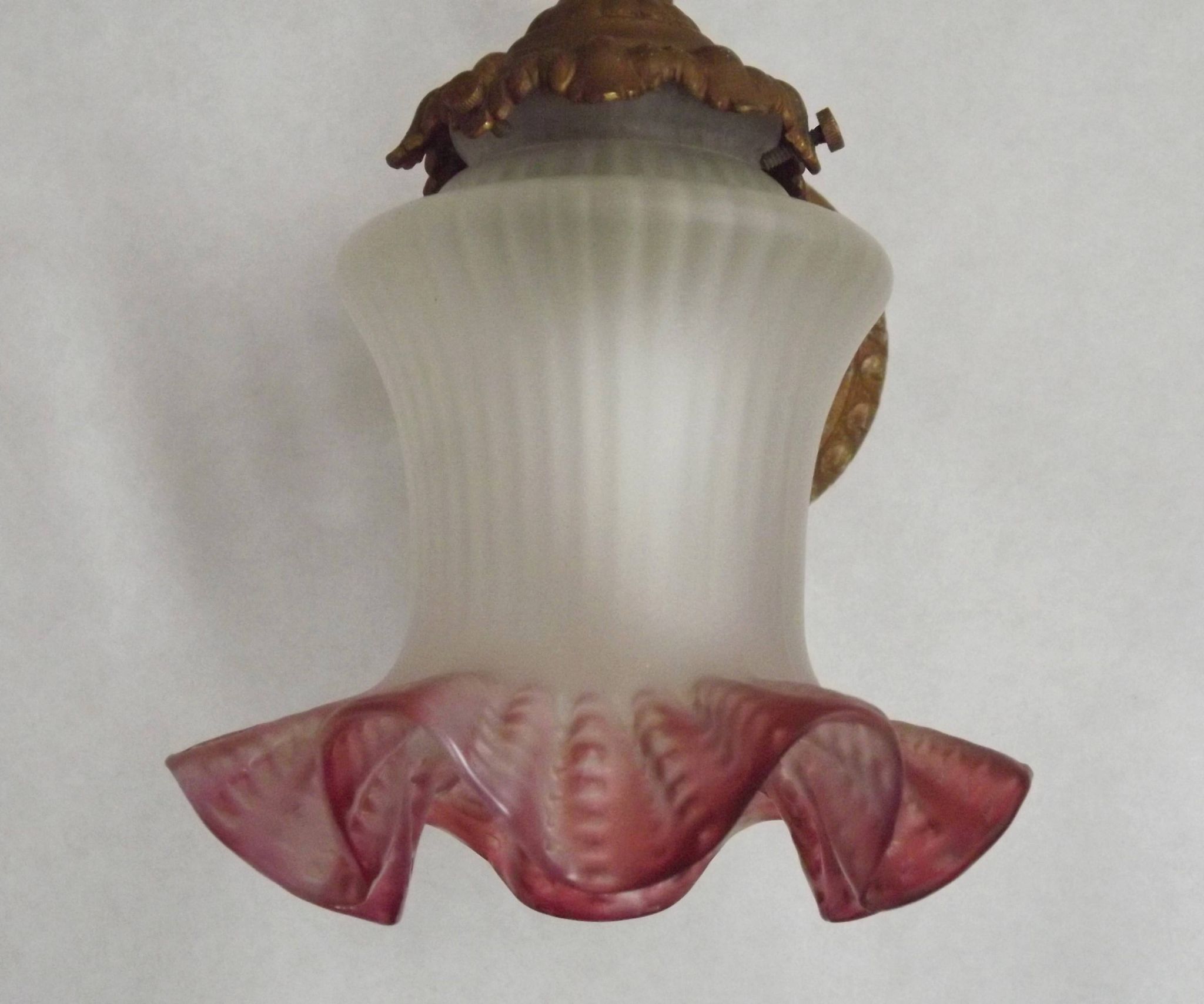 French Art Nouveau wall sconce in bronze with a white and pink glass shade.