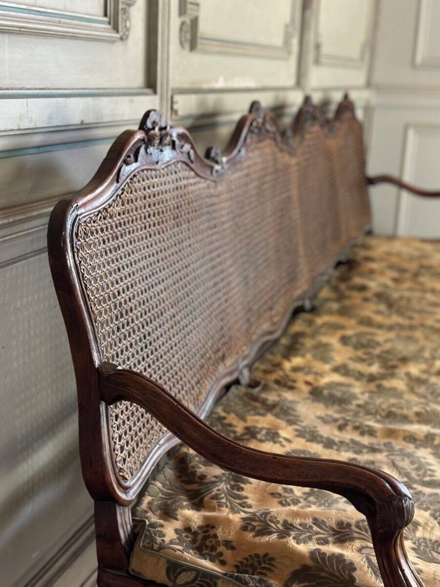 Grande banquette Louis XV en bois naturel mouluré et sculpté, France XVIIIème siècle