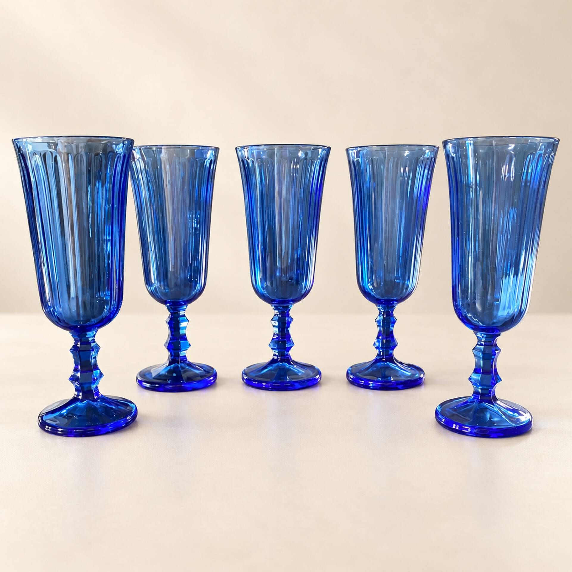Set of 5 blue glass champagne flutes with faceted stems.