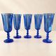 Set of 5 blue glass champagne flutes with faceted stems.