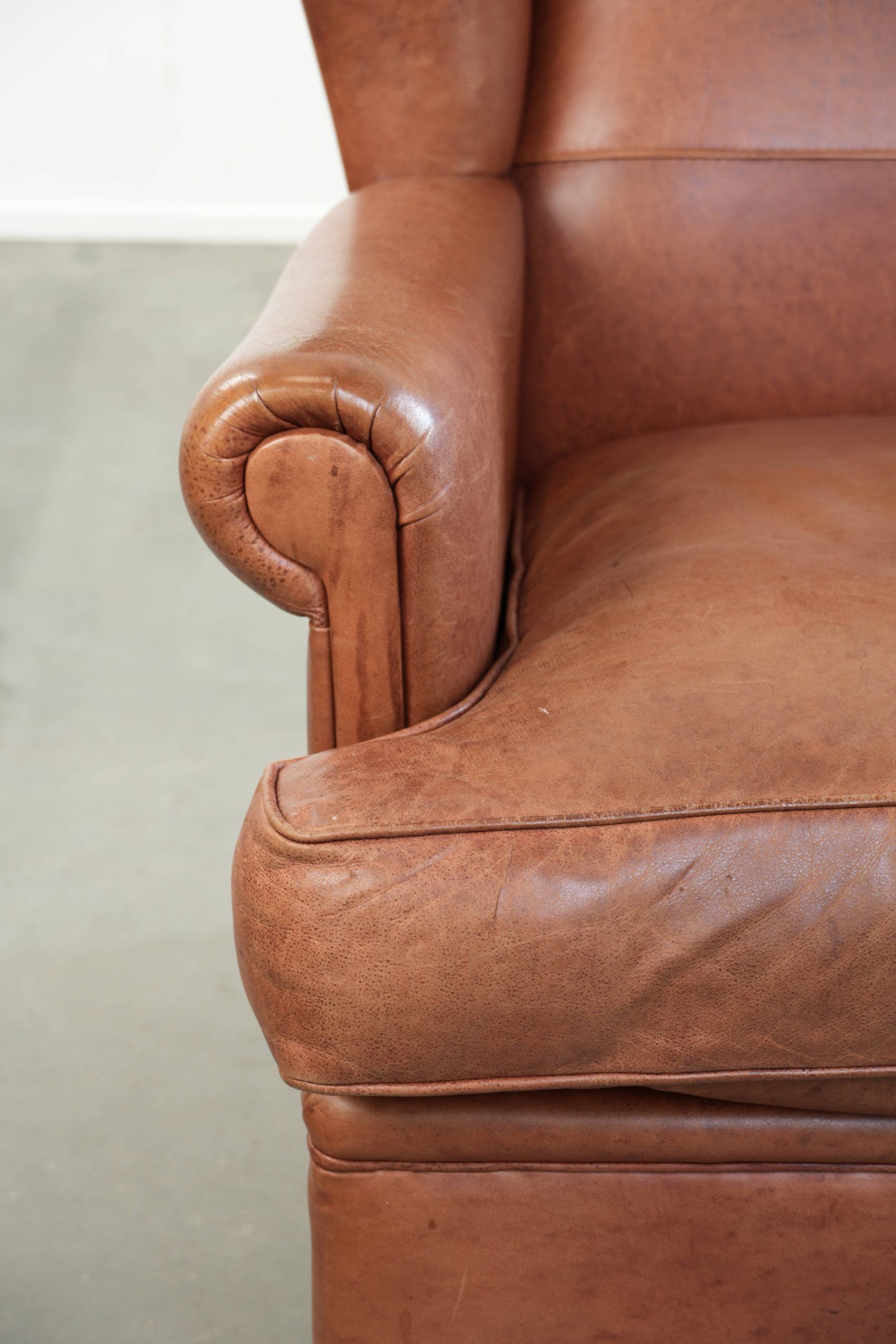 Fauteuil anglais à oreilles de couleur cognac clair en cuir de vache.