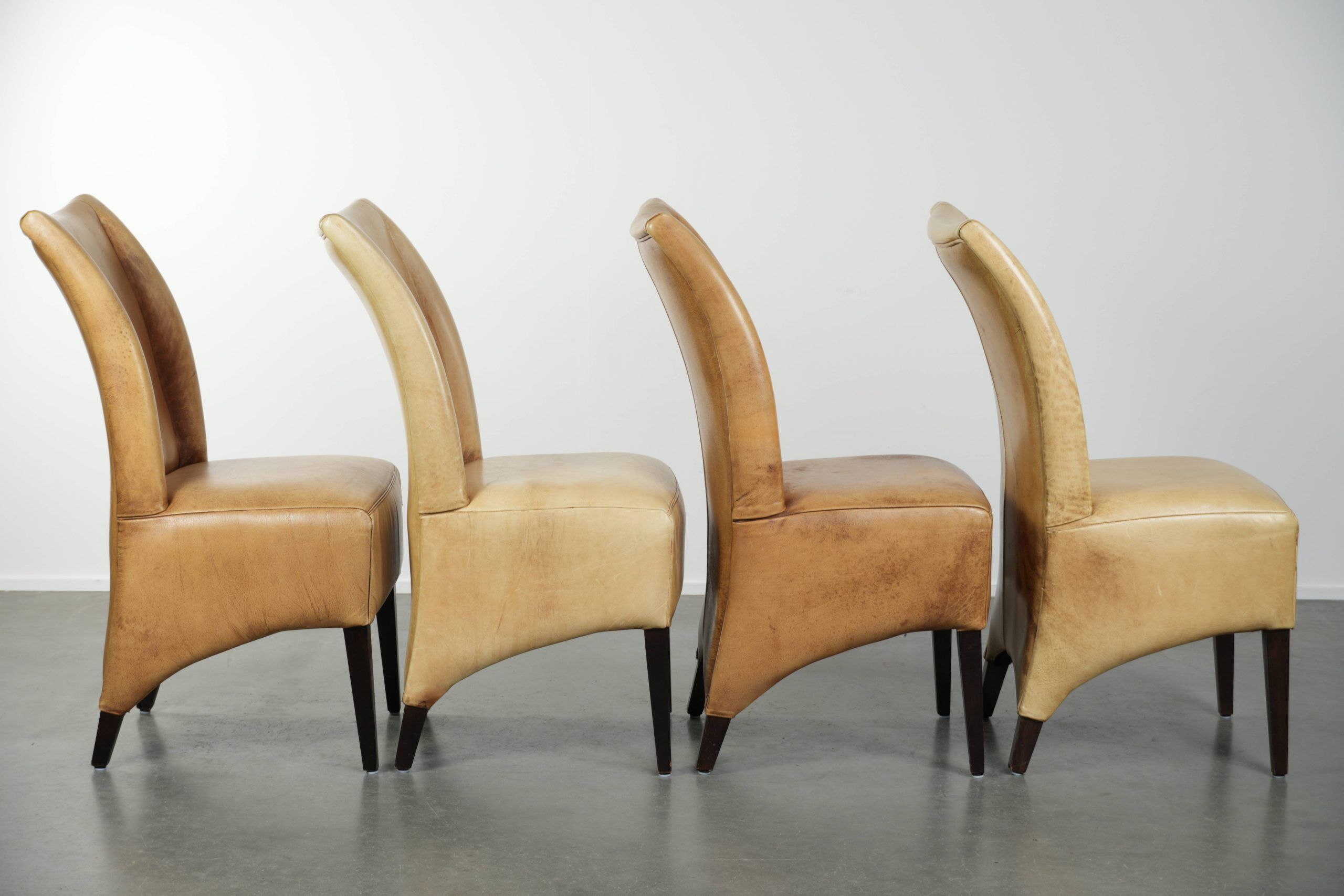 Ensemble de quatre chaises de salle à manger en cuir de vache avec un siège confortable et un dossier haut.