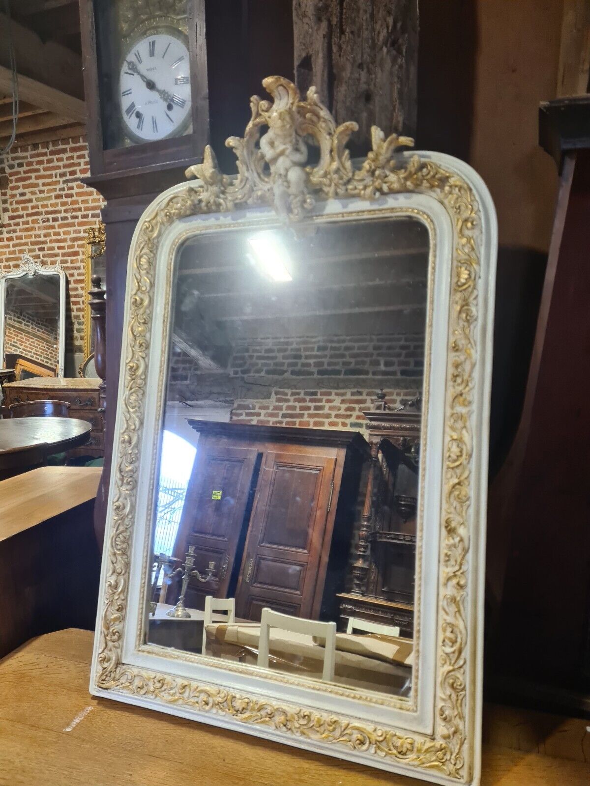 Patinated beige and gold mirror with an angel