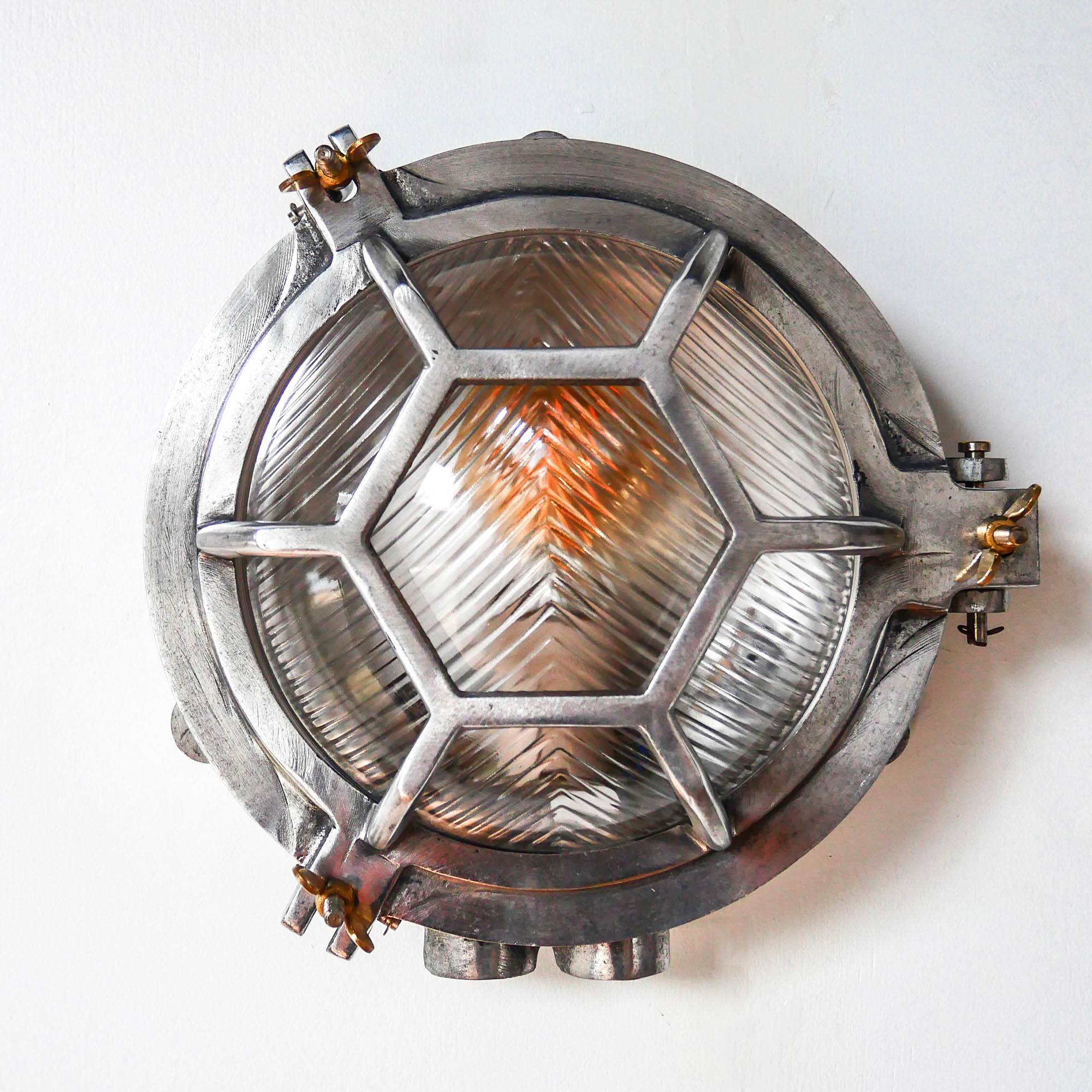 Old cast aluminum wall light with hexagonal grid and wide streaked glass.