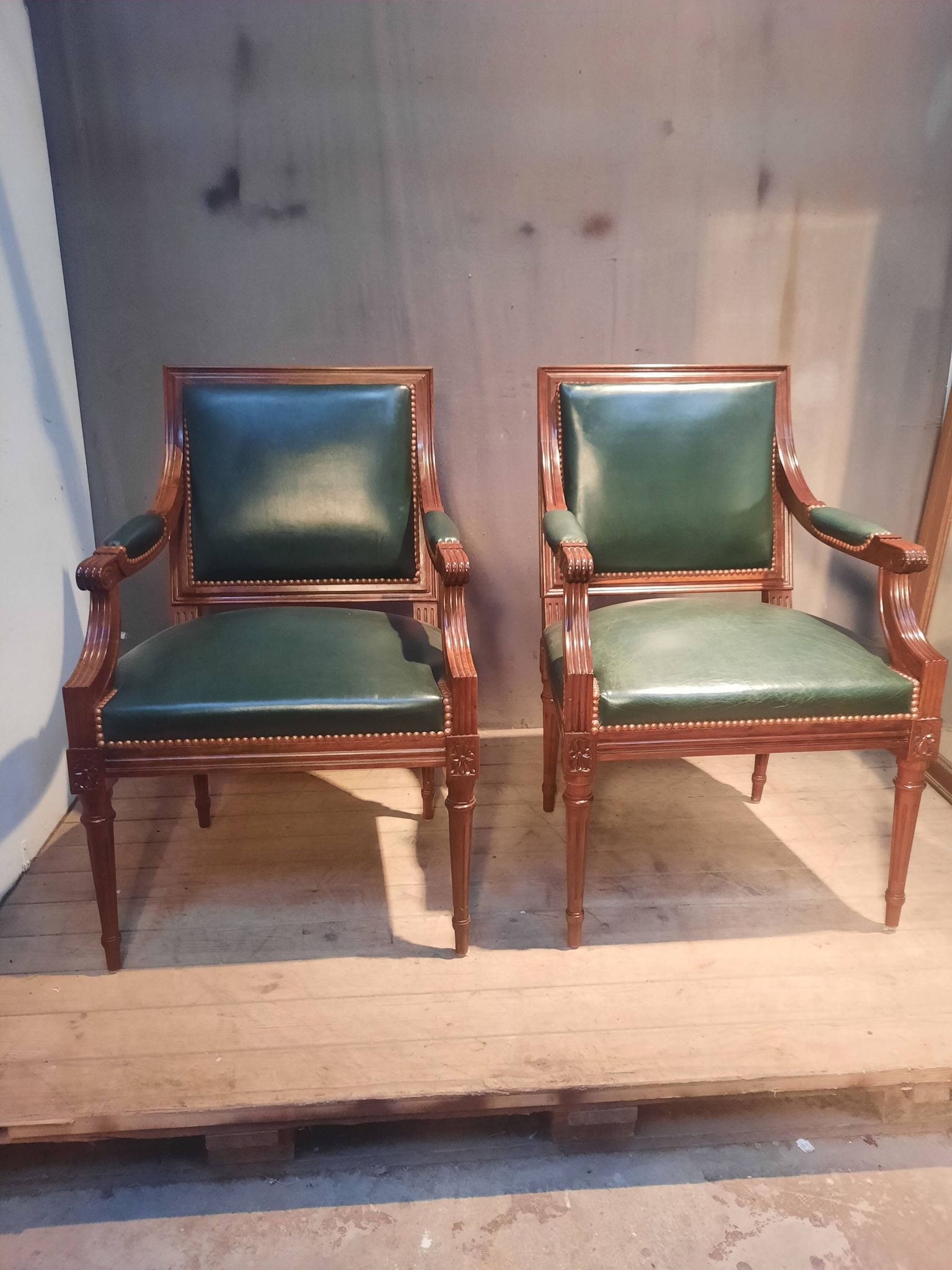 Pair of Louis XVI style armchairs upholstered in green leather.