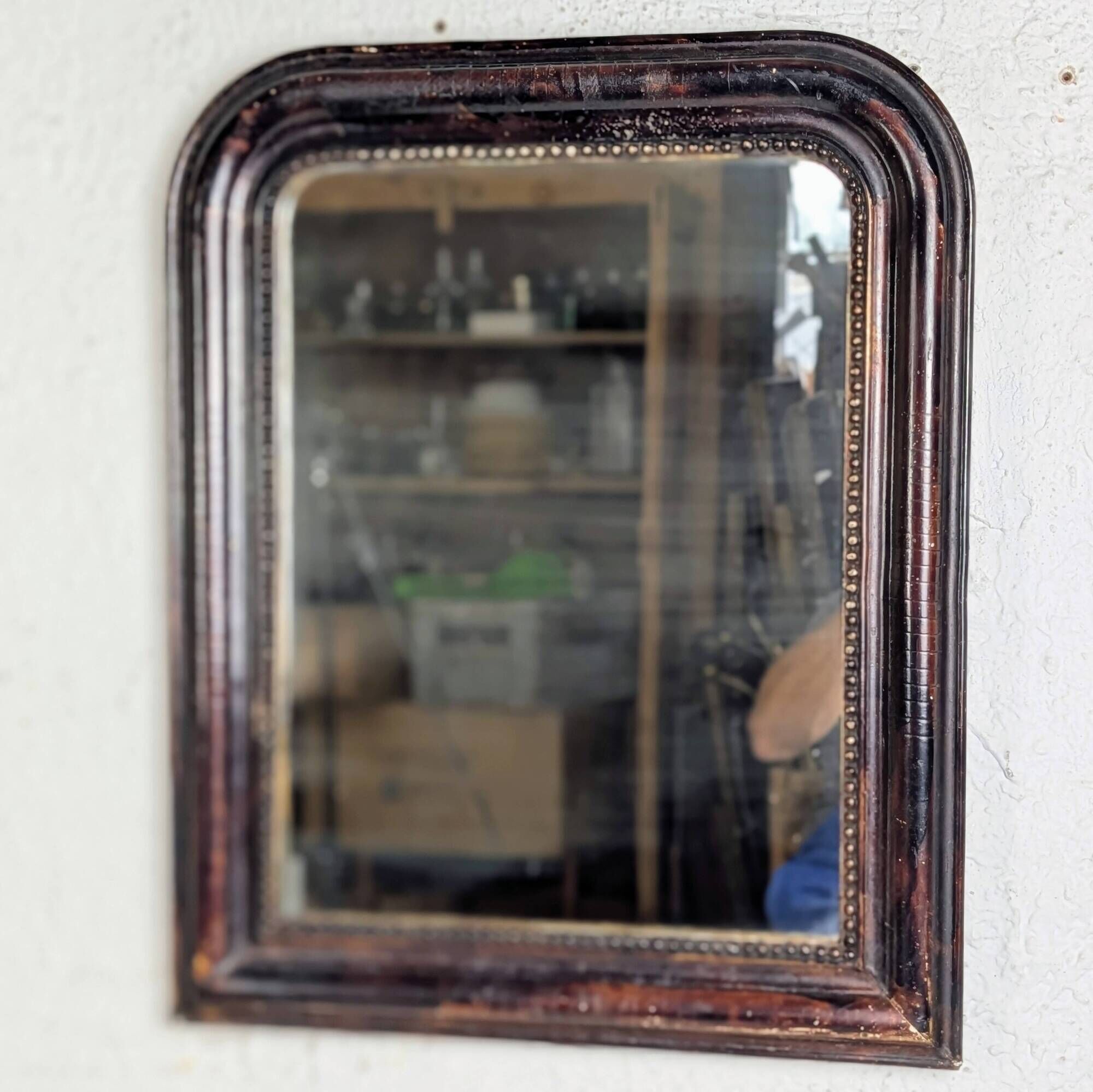 Antique Louis Philippe mirror with a patinated black frame.