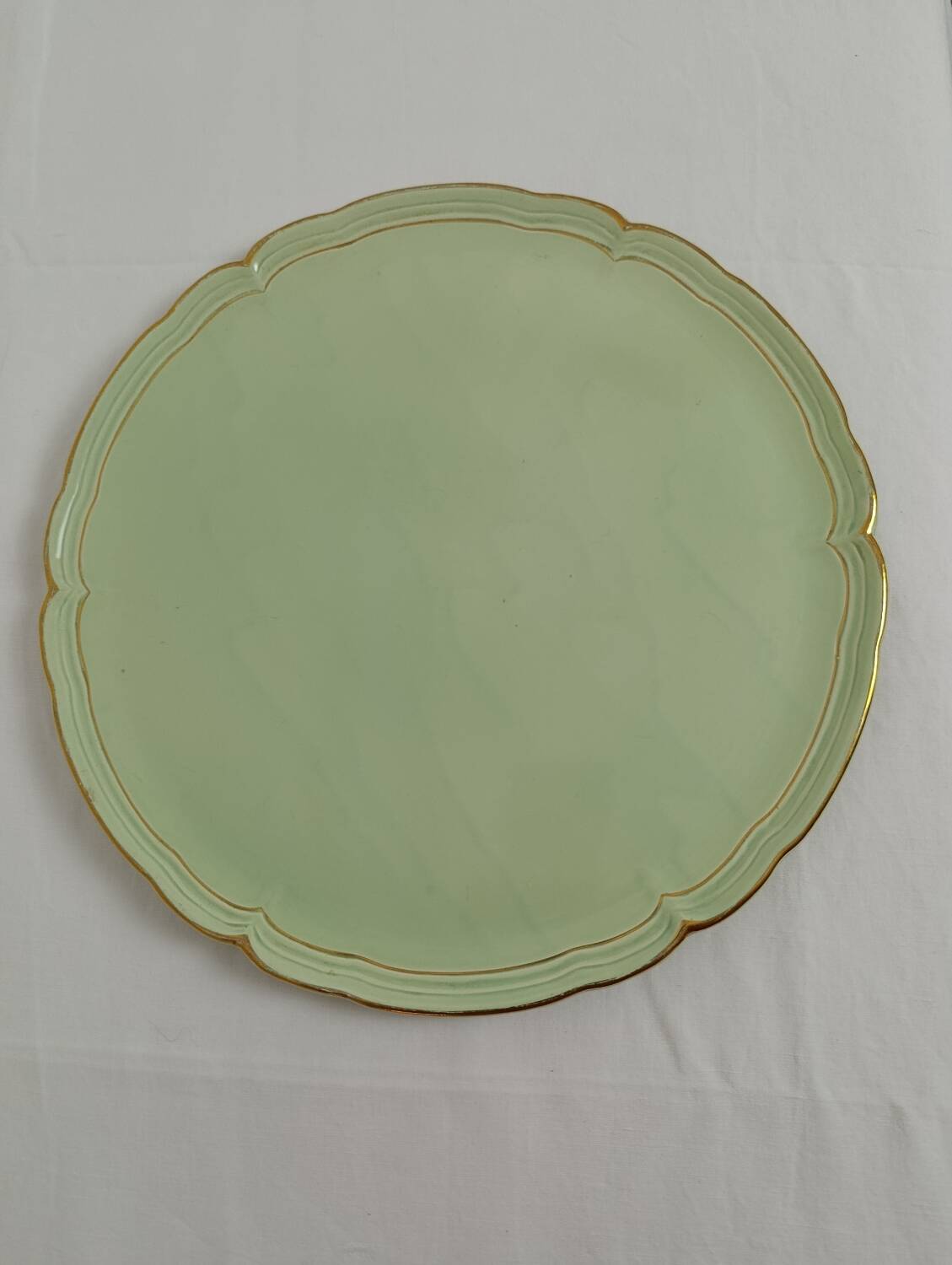 Large pastel green plate with a golden rim.