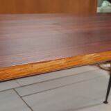 Table à manger en bois de teck et pieds en métal peint.
