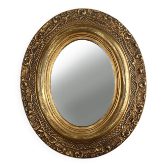 French Baroque style oval mirror in gilded wood with floral decorations