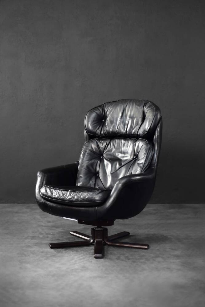 Vintage black leather swivel chair in mid-century modern Scandinavian style.