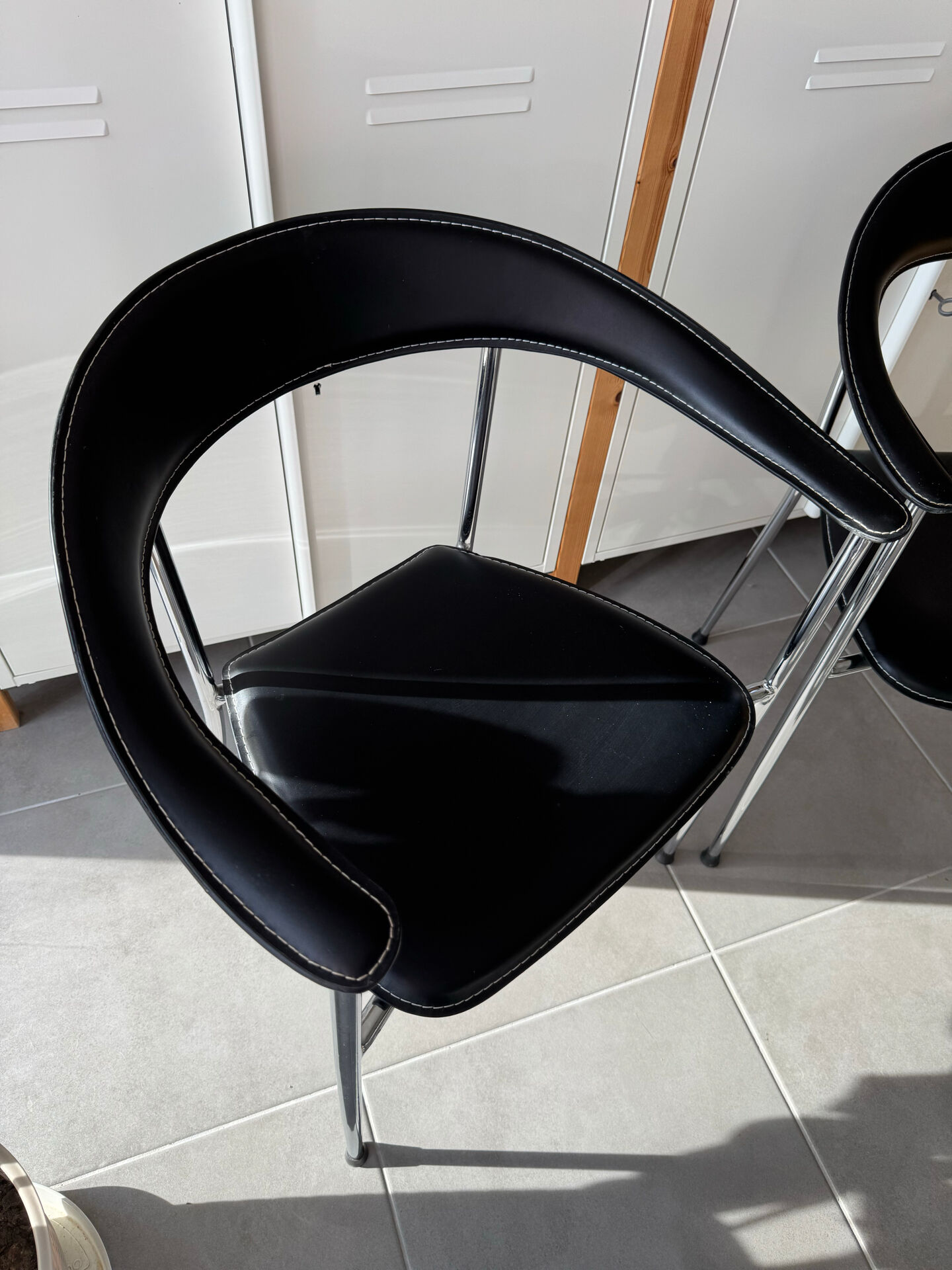 Set of two metal chairs with a brushed finish and black leather.