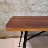 Table à manger en bois de teck et pieds en métal peint.