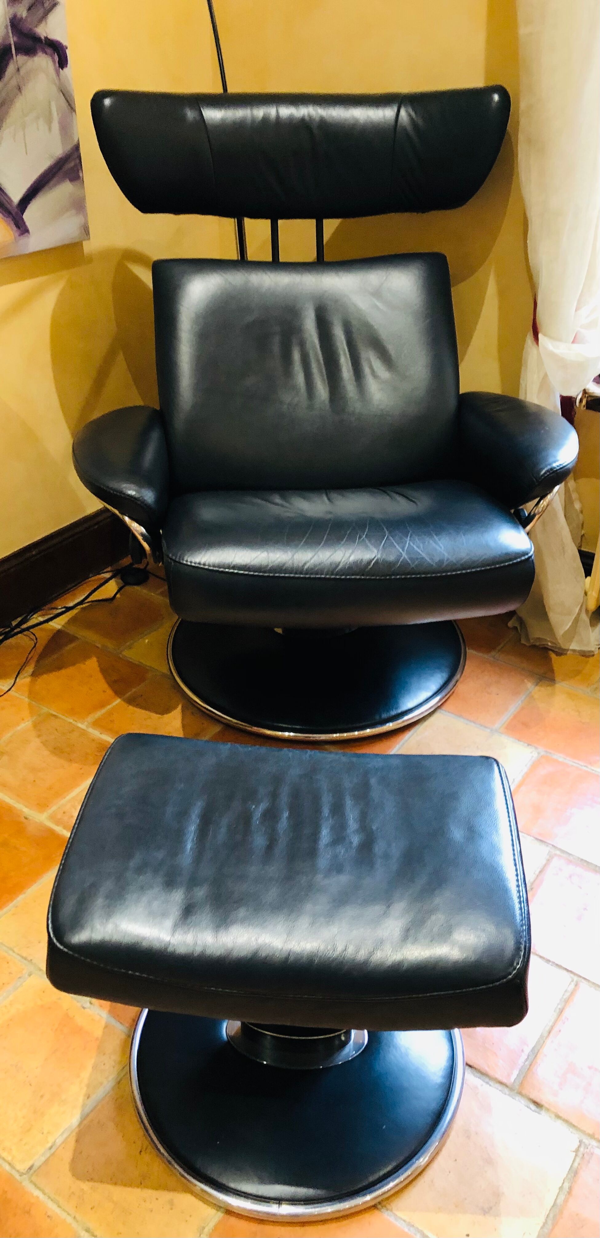 Black leather armchair stressless model jazz and its footrest