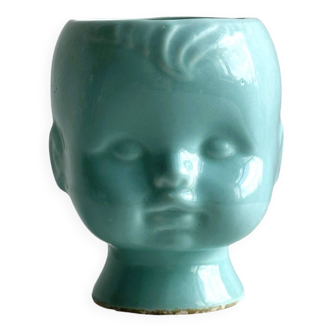 Turquoise plant pot in the shape of a vintage doll's head.
