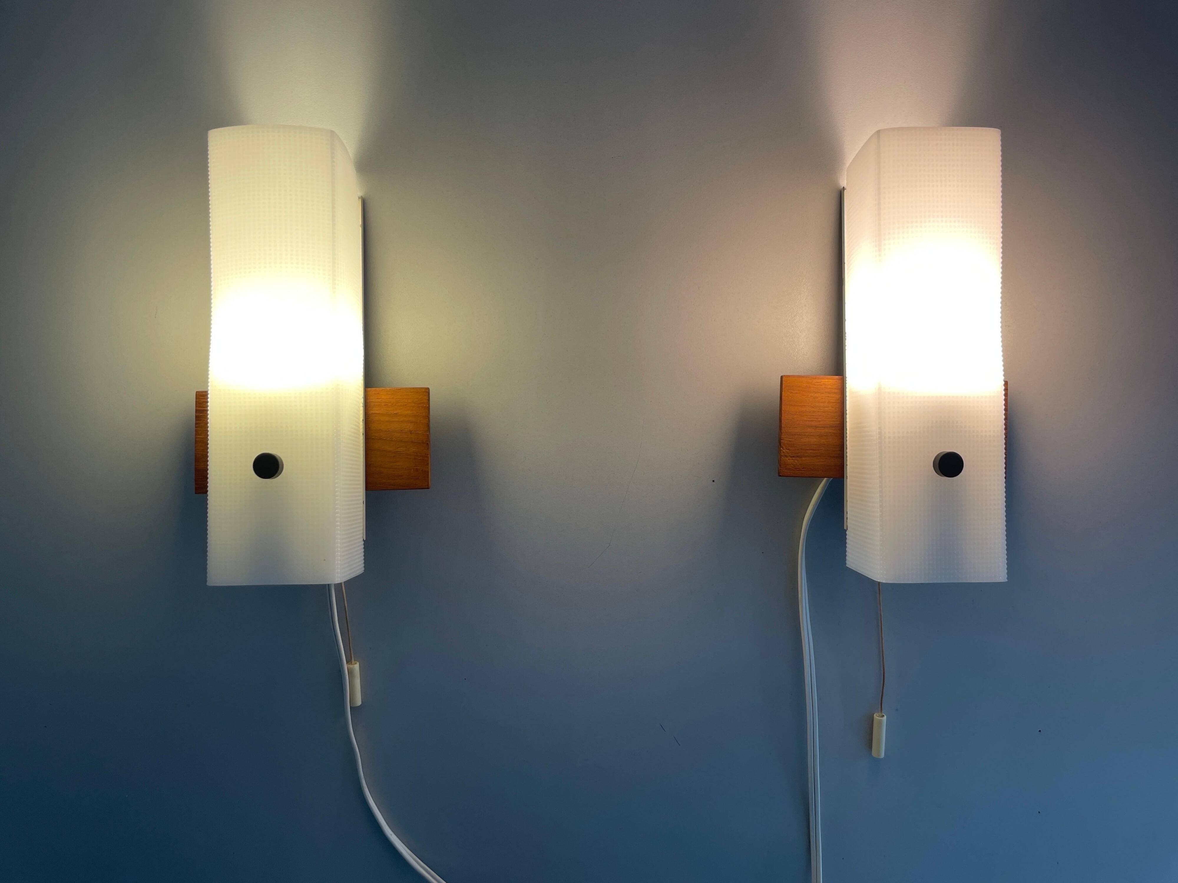 Mid-century wall lights in white plexiglass with a wooden base, 1960s, Germany.