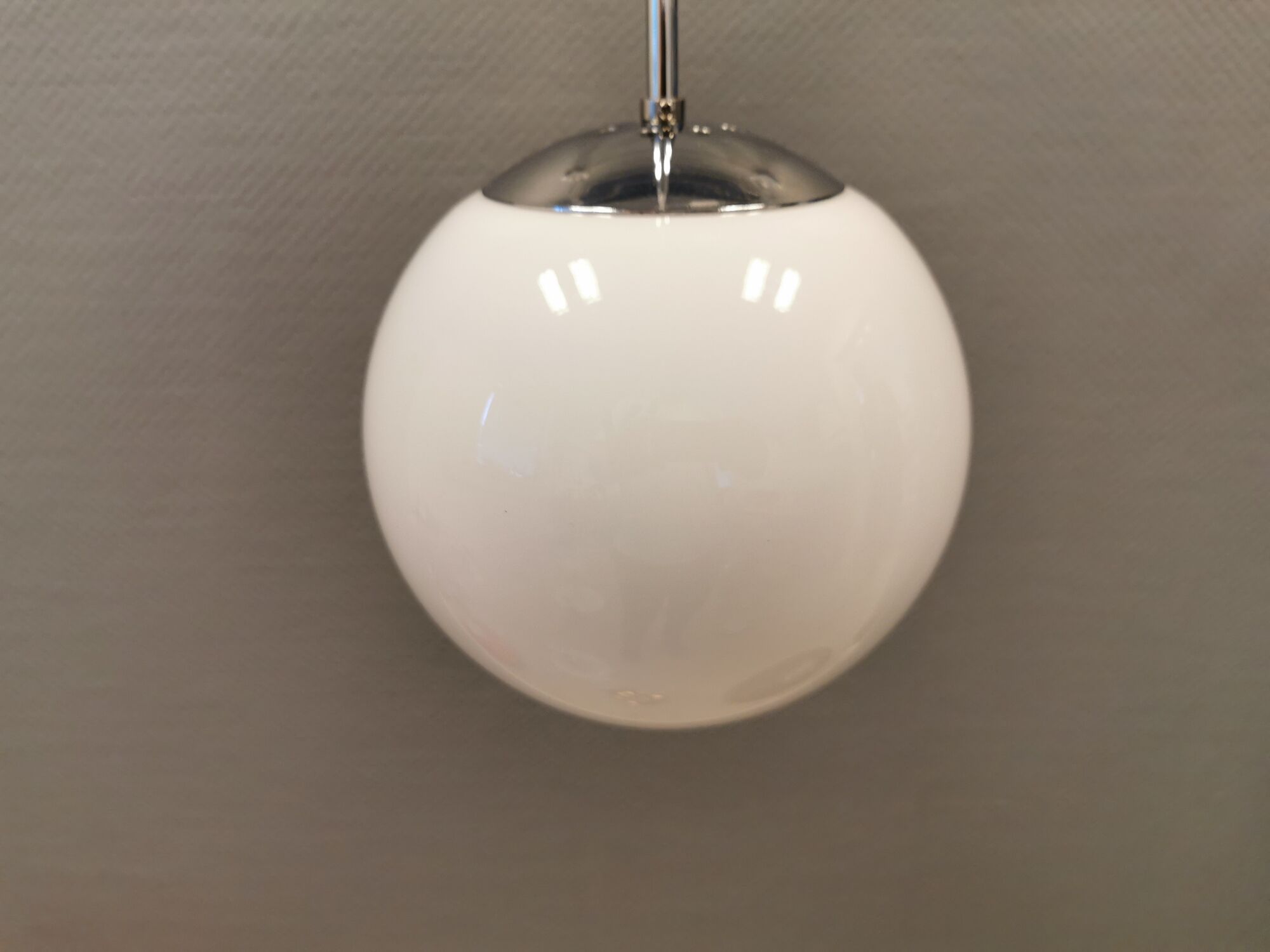 White hanging lamp with metal suspension, made with ball round opal glass shade.