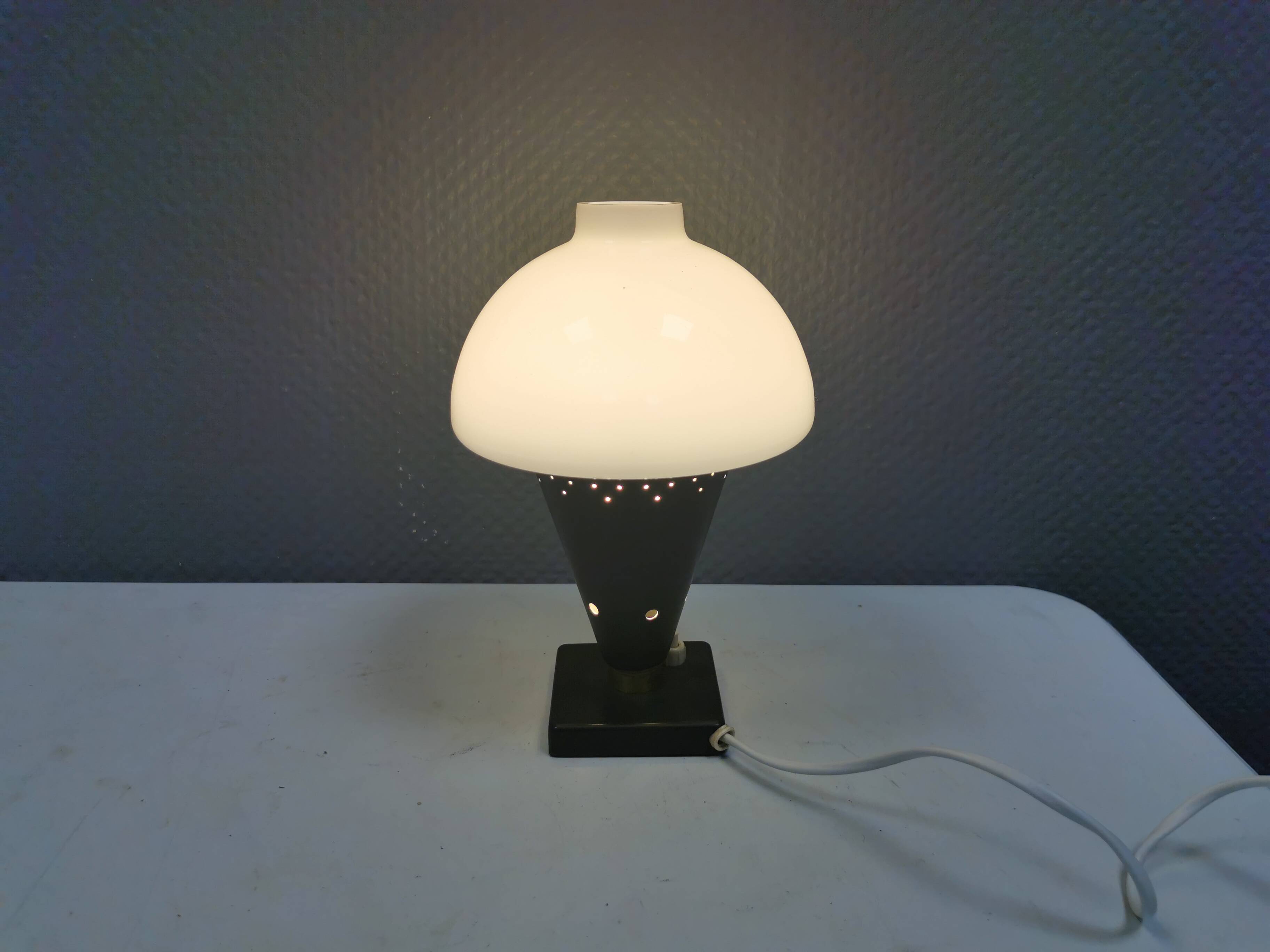 Small stylish table lamp with perforations and milky white opal glass shade